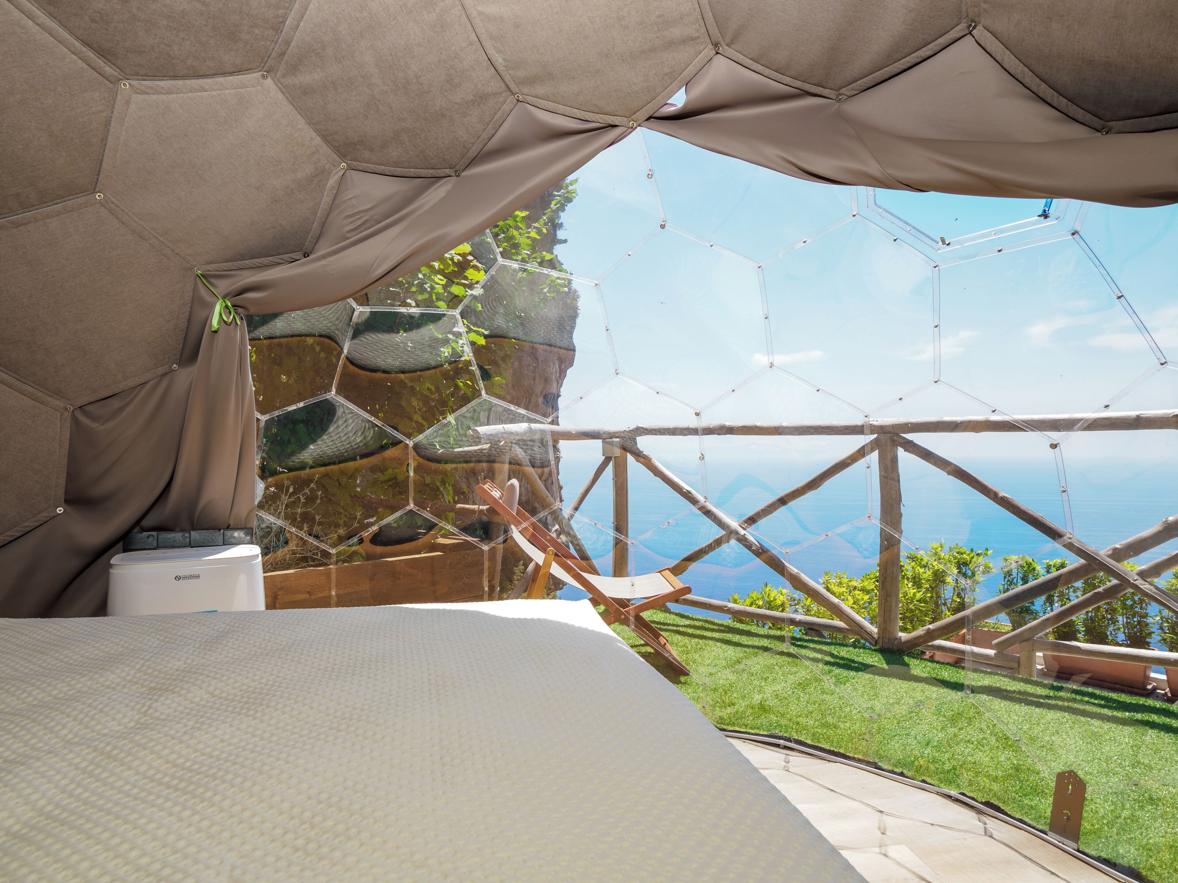 A room with a bed, a view of the outdoors, and a hexagonal structure.