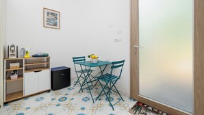 A small room with a table and chairs, a coffee machine, a kettle, and a framed picture on the wall. - De Vivo Realty - Boscosfera Amalfi (Amalfi)