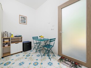 Une petite pièce avec une table et des chaises, une machine à café, une bouilloire et un tableau encadré au mur.