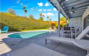 Ein Pool mit Liegestühlen und einer überdachten Terrasse.