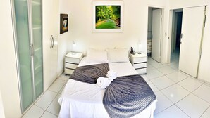 A hotel room with a bed, nightstands, a painting, and a bathroom door. - Vacanze - Don Felipe (Maceió)