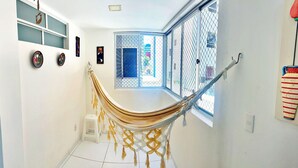 A room with a hammock, a window with a view, and wall decorations. - Vacanze - Don Felipe (Maceió)