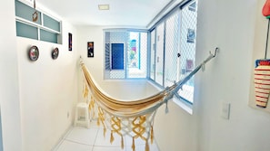 A room with a hammock, a window with a view, and wall decorations. - Vacanze - Don Felipe (Maceió)