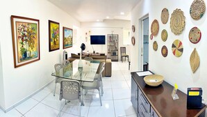 A modern living room with a glass dining table, a sofa, and a TV. - Vacanze - Don Felipe (Maceió)