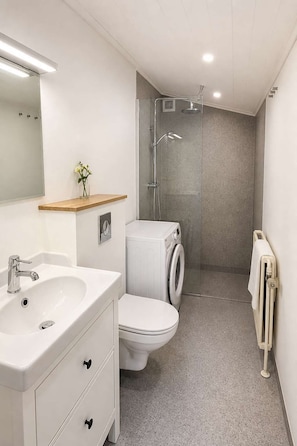 Un baño moderno con lavamanos, inodoro y ducha.