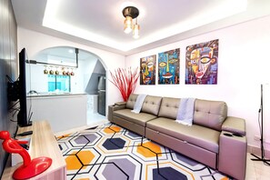 A modern living room with a sofa, a coffee table, and artwork on the wall. - 3-bedroom townhome in delightful Pattaya City with AC (Pattaya City)