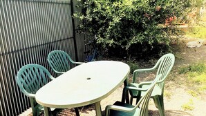 Une terrasse extérieure avec une table ronde et quatre chaises.