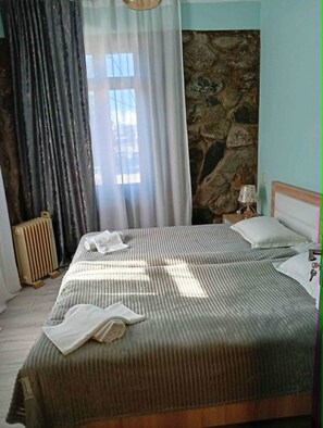 Un dormitorio con cama, pared de piedra, radiador y lámpara.