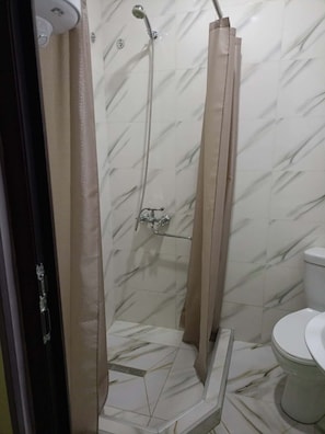Ein Badezimmer mit Dusche, Toilette und Handtuchhalter.