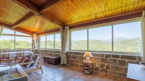 A room with a stone wall, large windows, a wooden ceiling, and a table with a lamp. - Character Stone House in the Heart of Medieval Montréal, Ardèche (Montréal)