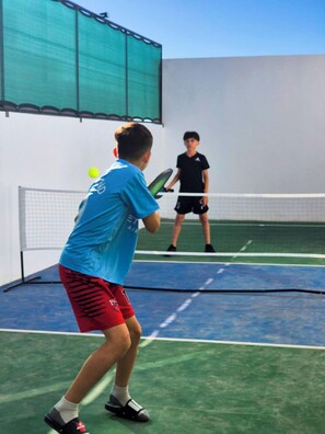 Ein Tennisplatz mit Netz, zwei Spielern und einem Tennisball.