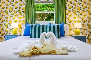 A hotel room with a bed, green curtains, a window with a view of greenery, and a lemon-patterned wallpaper. - Bradenton Vacation Haven | Pool, Hot Tub, Arcade (Bradenton)