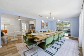 A dining area with a long table, chairs, and a chandelier. - Bradenton Vacation Haven | Pool, Hot Tub, Arcade (Bradenton)
