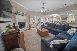 A spacious living room with a fireplace, a large sofa, a coffee table, and a television. - Isleview Retreat on Callendar Lake (Murchison)