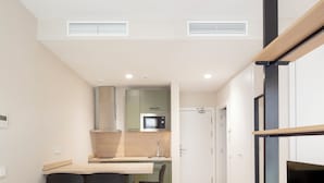 Un espacio habitable compacto con kitchenette, comedor y zona de estar.