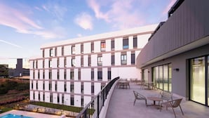 Un edificio moderno con balcón, zona de estar exterior y piscina.