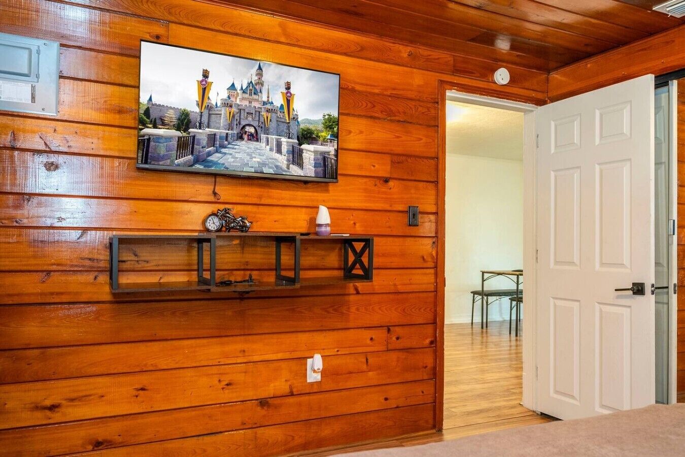 Ein Holzinterieur mit einem Wandbild einer Burg, einem Regal mit einem Motorrad und einer Tasse sowie einer weißen Tür.