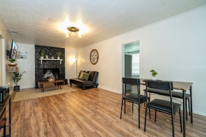 Una sala de estar con chimenea de piedra, un sofá, una mesa de centro y un comedor con sillas.
