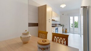 A modern kitchen with white cabinets, a dining table with chairs, and a view to the outside. - Holiday Home 'Il Giardino Dei Limoni' with Garden, Balcony, Parking, Pet Friendly (Sammichele di Bari)