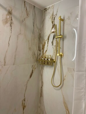 Een douche met gouden details en marmeren wanden.