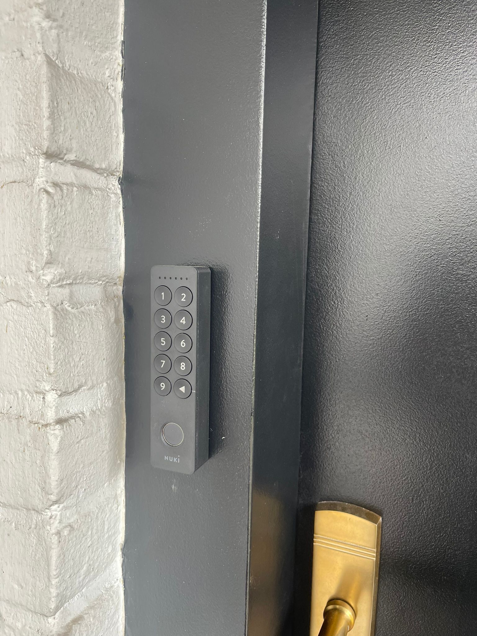 Cerradura electrónica con teclado y manija de latón.