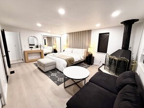 Ein modernes Hotelzimmer mit einem Bett, einem Sofa, einem kleinen Tisch, einem Kamin und einem Spiegel.