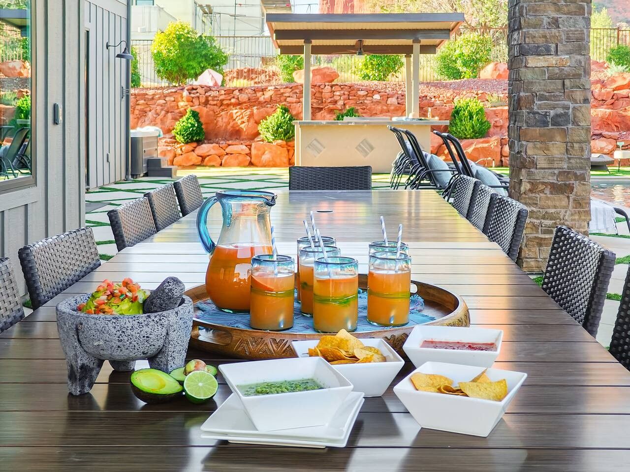 A dining table set with drinks, food, and a stone mortar and pestle.