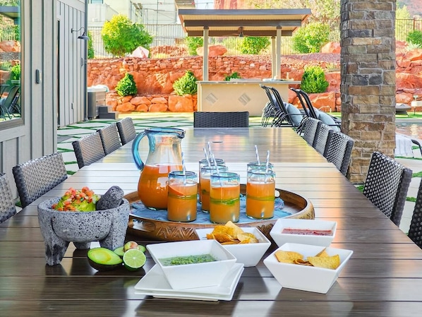 Una mesa de comedor dispuesta con bebidas, comida y un mortero y pilón de piedra.