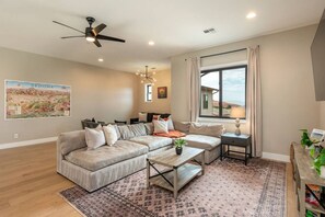 Una sala de estar moderna con un sofá modular, una mesa de centro, una mesita auxiliar y un amplio ventanal con cortinas.