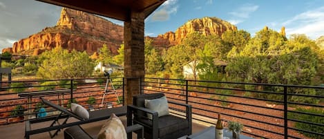 A covered outdoor seating area with a view of red rock formations and trees.