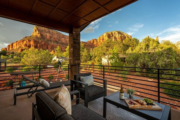 A covered outdoor seating area with a view of red rock formations and trees.