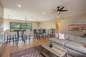 A modern living room with a sofa, coffee table, and dining area with chairs and tables.