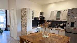 Una cocina moderna con armarios blancos, una mesa de comedor de madera y un refrigerador con imanes.