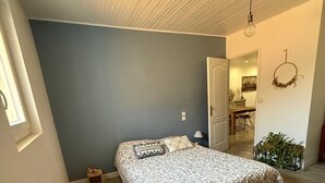 Un dormitorio con cama, radiador, suelo de madera, alfombra estampada y techo con diseño lineal.