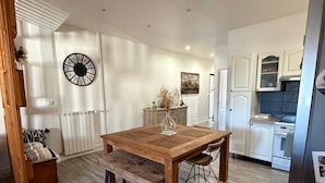 Una cocina moderna con armarios blancos, una mesa de comedor de madera y un horno empotrado.