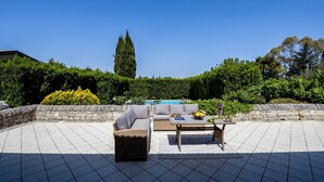 An outdoor patio with a stone wall, a pool, a sofa, and a table with fruits and a vase. - Villa Rebecca - Modica (Modica)