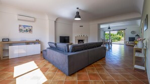 A living room with a sofa, a TV, a fireplace, and a dining area with chairs. - Villa Rebecca - Modica (Modica)