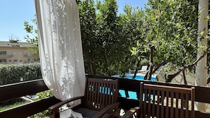 A balcony with a view of a swimming pool, wooden chairs, and a white curtain. - Appartamento Miranda Oro - Caste... (Castellammare del golfo)