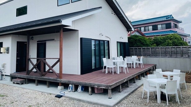 Ein modernes Gebäude mit überdachter Außenbereich-Sitzgelegenheit und einer Holzterrasse.