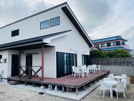Un edificio moderno con un espacio de estar al aire libre techado y una terraza de madera.