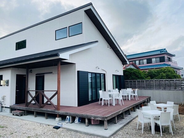 A modern building with a covered outdoor seating area and a wooden deck. - THE Erabu (Wadomari)