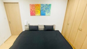 Ein Schlafzimmer mit einem Bett, einem Holzschrank und einem farbenfrohen Wandbild.