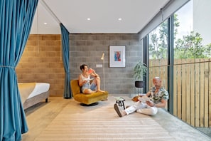 Ein modernes Zimmer mit einem Bett, einer Schlafcouch, einem kleinen Tisch und einem großen Fenster.