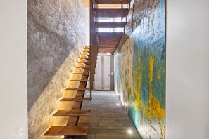 A narrow hallway with a wooden staircase leading to a door. - The 21 - Gaia by Homie (Ribeira Brava)