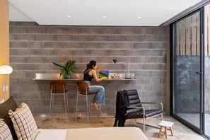 A modern room with a brick wall, a desk with a laptop, a chair, and a sofa. - The 21 - Gaia by Homie (Ribeira Brava)