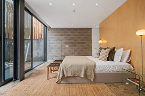 A modern bedroom with a large bed, a wooden accent wall, and a view through floor-to-ceiling windows. - The 21 - Gaia by Homie (Ribeira Brava)