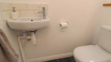 A bathroom with a white sink, toilet, and dark tiled floor.