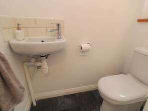 A bathroom with a white sink, toilet, and dark tiled floor. - The Joinery (Scarborough)
