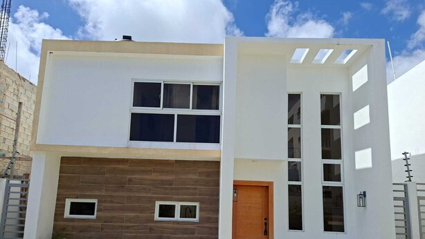 A modern two-story house with a wooden facade, a front door, and a small porch area. - 3-bedroom house in charming Punta Cana with cool AC (Punta Cana)