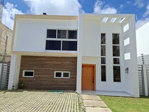 Une maison moderne à deux étages, dotée d’un toit plat, de grandes fenêtres et d’une façade en bois.
